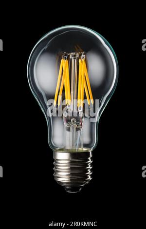 Modern transparent LED filament bulb isolated on black background. Stock Photo