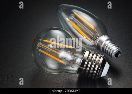 Old-fashion transparent LED filament bulbs on black background. Stock Photo