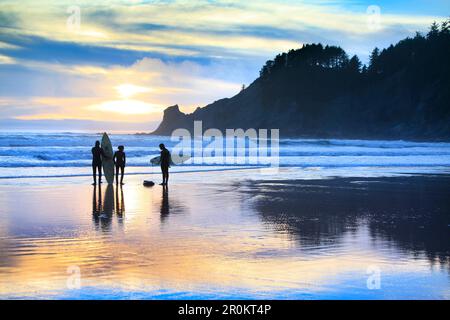 USA, Oregon, Oswald West State Park, surfers walk along the beach and out into the water at Oswald State Park, just south of Cannon Beach Stock Photo