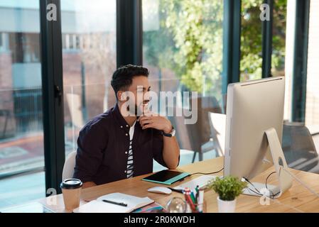 I always get funny emails from clients. a handsome young businessman sitting alone in the office and working on his computer. Stock Photo