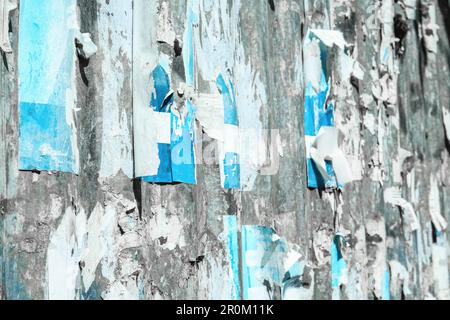 Old wall with flaky paint and torn advertisements as background, closeup Stock Photo