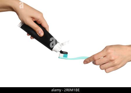 Woman applying charcoal toothpaste on brush against white background, closeup Stock Photo