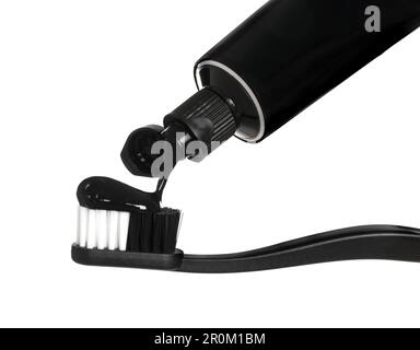 Applying charcoal toothpaste on brush against white background Stock Photo