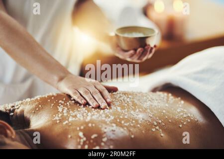 Woman, hands and relax in salt scrub for skincare, exfoliation or relaxation at indoor beauty spa. Hand of masseuse rubbing salts on female back for Stock Photo