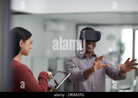 Our customers are going to love this game. two young colleagues using a digital tablet and a virtual reality headset in a modern office. Stock Photo