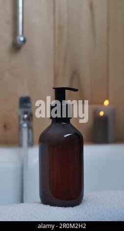 Black bottle of bubble bath and candles on tub indoors Stock Photo