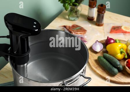 Sous vide cooker in pot and ingredients on table, closeup. Thermal immersion circulator Stock Photo