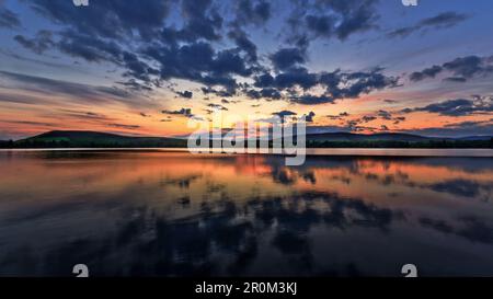 A stunning mirror like reflection of a Sunset over the water at the picturesque Loch of Lintrathen, Angus, Scotland. Stock Photo