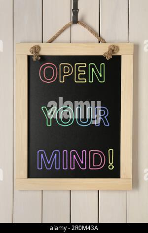 Small chalkboard with motivational quote Open your mind hanging on white wooden wall Stock Photo
