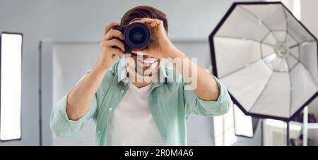Young male photographer using professional camera in studio Stock Photo