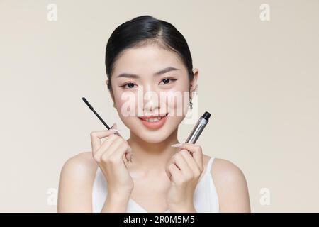 Charming young woman applying mascara. Stock Photo