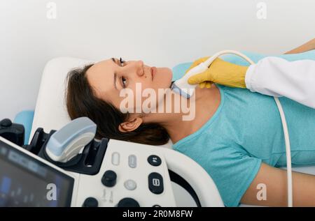 Ultrasound diagnostics of thyroid gland. Endocrinologist making ultrasonography to female patient at ultrasound office of medical clinic Stock Photo