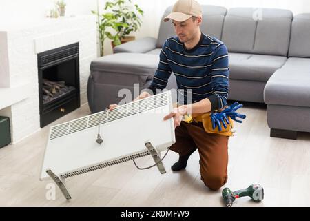 the master repairs the electric heater Stock Photo