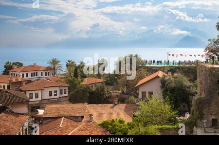 People stand on a viewing platform built on top of the city walls to look out over the red rooftops of the ancient old town of Kaleici and the Mediter Stock Photo