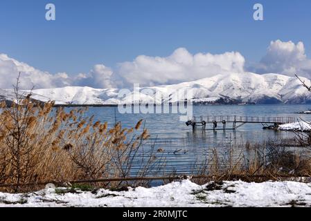 Jetty on the shore of the lake, view from the Sevan peninsula with snowy mountains, Lake Sevan, Armenia, Asia Stock Photo