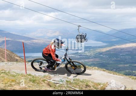 Downhill Mountain biker riding at the Nevis Range Mountain Resort with view of the Great Glen and Fort William behind, Fort William, Scotland, UK Stock Photo