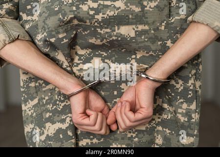 Handcuffed soldier in military army clothes. Close up of hands in handcuffs Stock Photo