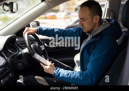 Smartphone man in car driving showing smart phone display smiling happy. Male driver using app showing blank empty screen sitting in drivers seat Stock Photo