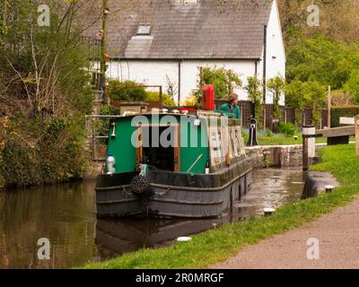 Woman steering narrowboat out of Brynich lock on Monmouthshire and Brecon canal on way to Brecon town in Brecon Beacons National Park Powys Mid Wales Stock Photo
