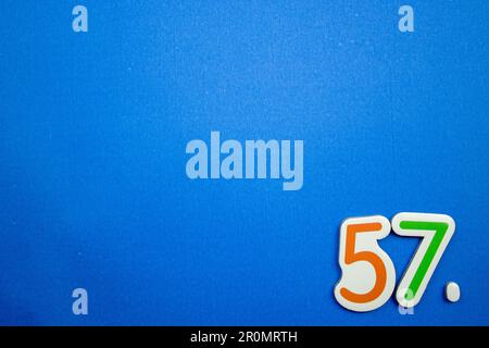 The number 57, placed on a blue background, photographed from above ...