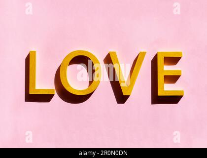 3d yellow love text written in capital letters on vivid pastel pink background Stock Photo