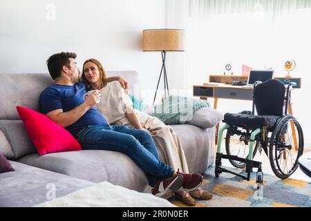 Loving couple cuddling and relaxing together on comfortable sofa in living room while talking Stock Photo