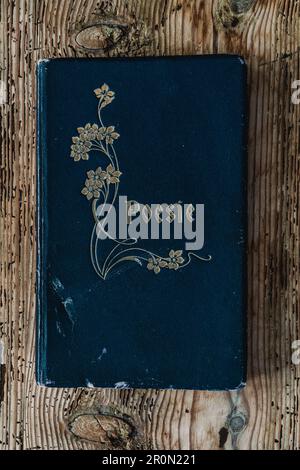 From above view of ancient used blue poem volume placed on wood background Stock Photo