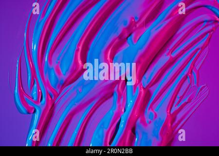 From above puddle of bright neon acrylic paint spread on vivid purple background Stock Photo