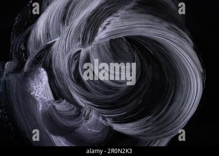 From above smears of white pigment spread chaotically on black surface Stock Photo