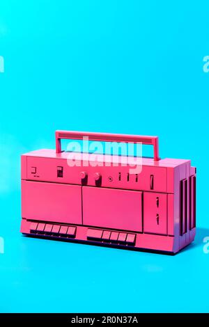 Close-up viewing of bright pink retro cassette tape recorder placed in studio against blue background Stock Photo