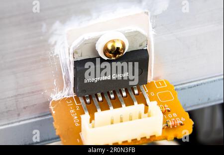 Close up macro of IC integrated circuit attached to aluminum heat sink on electronic circuit board. concept of electronic components Stock Photo