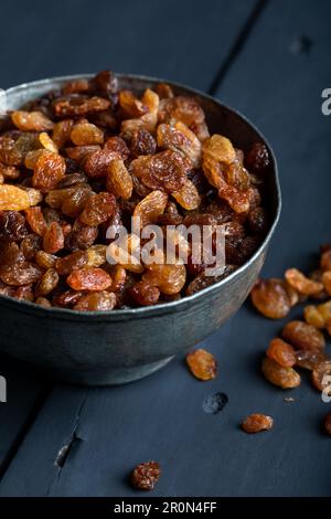 Dried grapes, raisins in a bowl on dark wooden background. Stock Photo