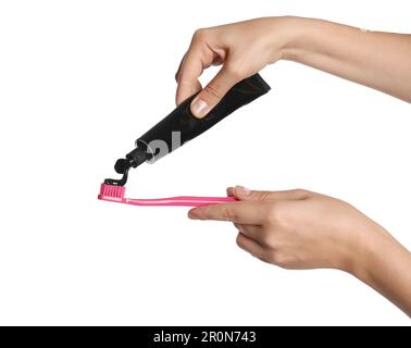 Woman applying charcoal toothpaste on brush against white background, closeup Stock Photo