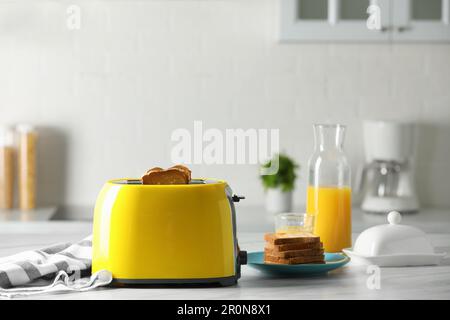 https://l450v.alamy.com/450v/2r0n8x1/yellow-toaster-with-roasted-bread-slices-and-orange-juice-on-white-marble-table-2r0n8x1.jpg