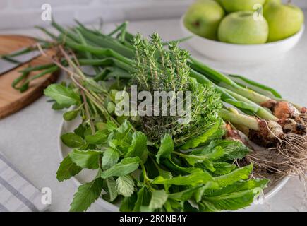 Fresh picked garden herbs such as spring onions, thyme and mint on a kitchen counter Stock Photo