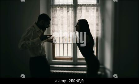 Silhouette of couple fighting each other, arguing and yelling at one another. Young man and woman shouting in anger. Candid behind closed doors Stock Photo