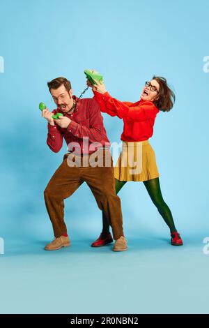 Portrait with married couple, guilty man and angry woman wearing vintage clothing quarrelling over blue studio background Stock Photo