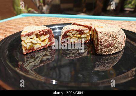Slices of Anjeer cake, Indian sweet dish item covered with poppy seeds. Fig dessert with filling of dates, cashewnuts almonds and pista Stock Photo