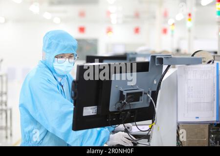 CHONGQING, CHINA - MAY 9, 2023 - Workers watch the production of electronic chips through an electronic display at the production workshop of the Radi Stock Photo