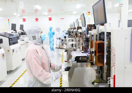 CHONGQING, CHINA - MAY 9, 2023 - Workers watch the production of electronic chips through an electronic display at the production workshop of the Radi Stock Photo