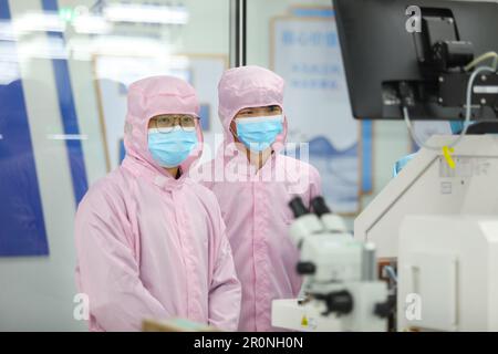 CHONGQING, CHINA - MAY 9, 2023 - Workers watch the production of electronic chips through an electronic display at the production workshop of the Radi Stock Photo