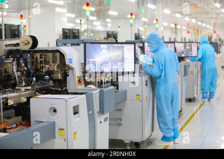 CHONGQING, CHINA - MAY 9, 2023 - Workers watch the production of electronic chips through an electronic display at the production workshop of the Radi Stock Photo