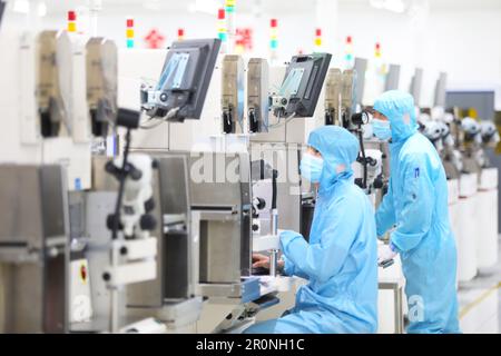 CHONGQING, CHINA - MAY 9, 2023 - Workers watch the production of electronic chips through an electronic display at the production workshop of the Radi Stock Photo