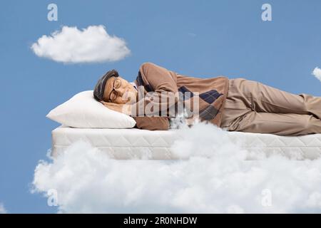 Elderly man sleeping on a matress and floating on clouds Stock Photo