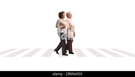 Full length profile shot of two elderly ladies walking at a pedestrian crossing isolated on white background Stock Photo