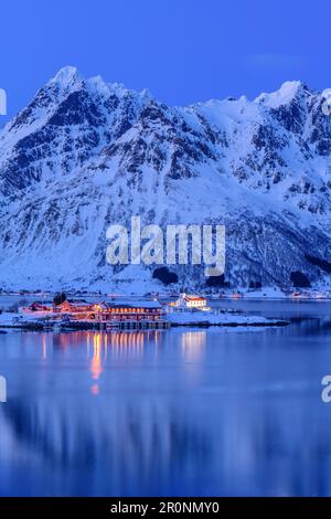 Illuminated slidpollnes and snowy mountains are reflected in fjord, Lofoten, Nordland, Norway Stock Photo