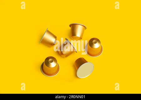 Six golden colored coffee capsules on a yellow background with copy space Stock Photo