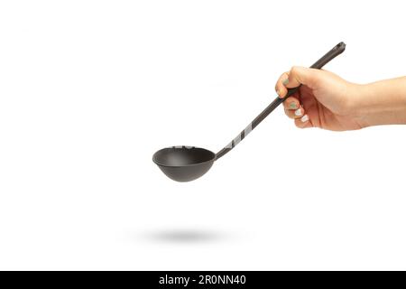 Woman hand holding a black plastic ladle on a white background with copy space Stock Photo