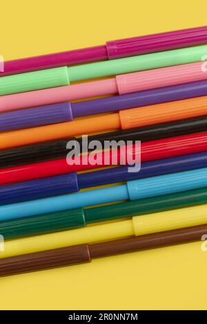 Colored markers on a yellow background in a close up view with copy space Stock Photo