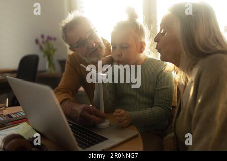 Senior couple doing homework with their granddaughter. Stock Photo